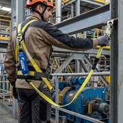 Trabajador con arnés y amortiguador de impacto azul JYRSA SS-AMC1-1M83CM conectando banda amarilla en planta industrial - DIBAMEX